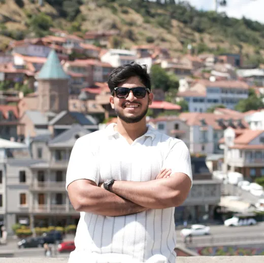 Joalex Joji Padiken smiling with arms crossed, hillside old town in the background